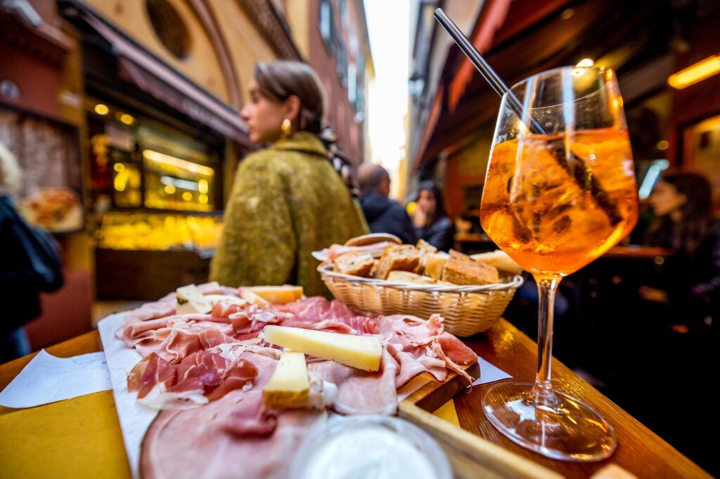 deska lokalnych serów i wędlin, chrupiące przekąski i spritz czyli aperitivo na Via Pescherie Vecchie, Bolonia, Emilia-Romania, Włochy