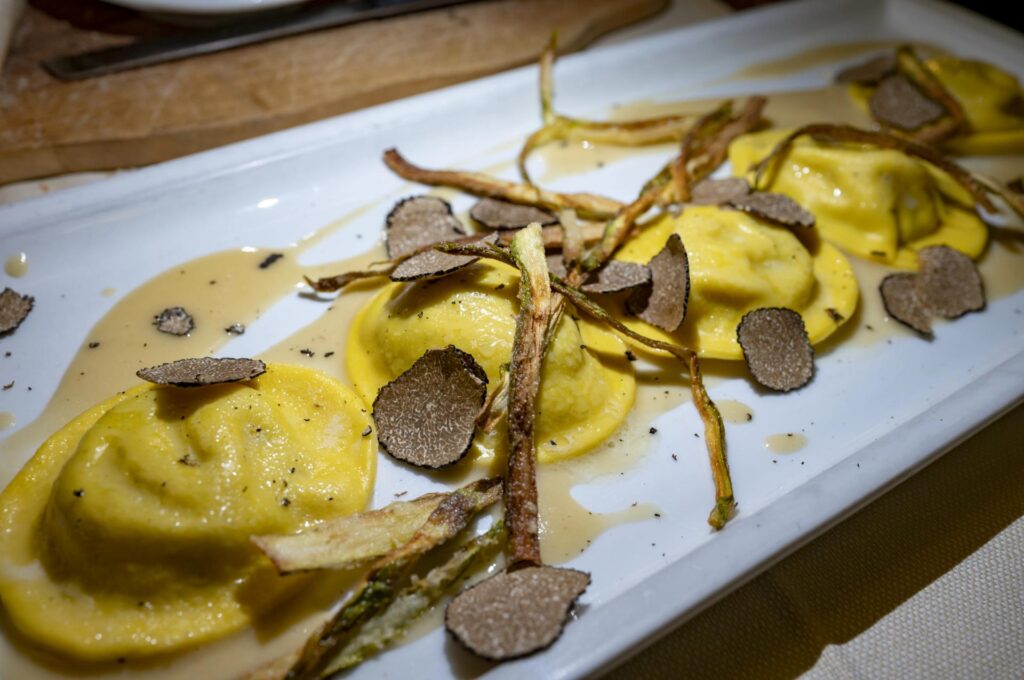 okrągłe pierożki ravioli z czarną truflą (tartufo nero) i chipsami ze szparagów - Emilia-Romania słynie nie tylko z wielu rodzajów pierożków, ale też z łatwej dostępności trufli